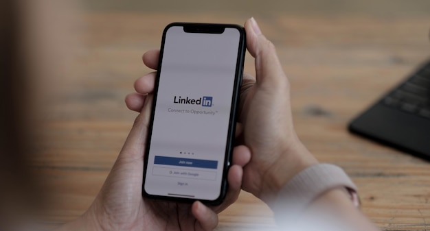 CHIANG MAI, TAILANDIA, 24 DE AGOSTO DE 2021: Una mujer sostiene un iPhone X de Apple con la aplicación LinkedIn en la pantalla. LinkedIn es una aplicación para compartir fotos para teléfonos inteligentes.