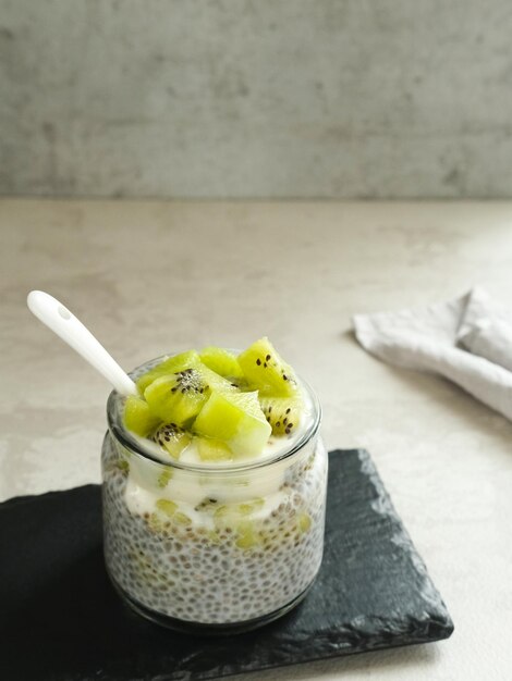 Chiaseed servido em um frasco de vidro coberto com iogurte e kiwi Muito fresco e saudável