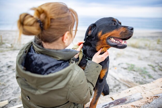 Chica abrazando a un perro Rottweiler en la playa