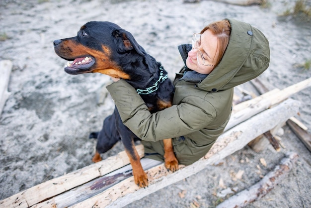 Chica abrazando a un perro Rottweiler en la playa