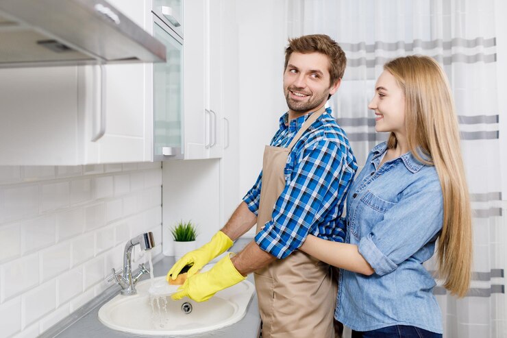 Chica abrazando a su esposo mientras lava los platos