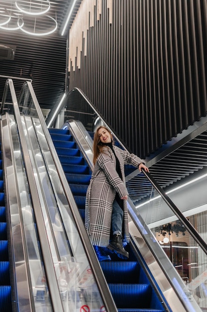 una chica con abrigo baja por la escalera mecánica