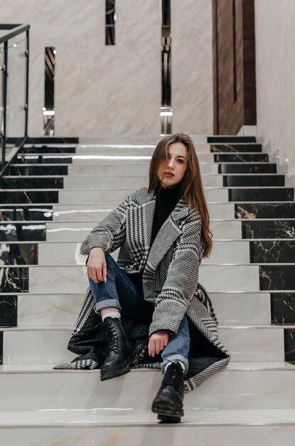 una chica con abrigo se sienta en las escaleras