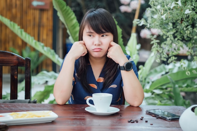 Chica aburrida cansada sentado y bebiendo café en un café al aire libre y mirando a otro lado