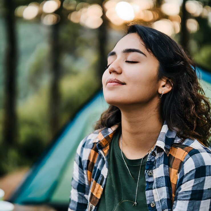 Foto chica acampando en el bosque mientras cierra los ojos y respira el concepto de vacaciones de aire fresco nat