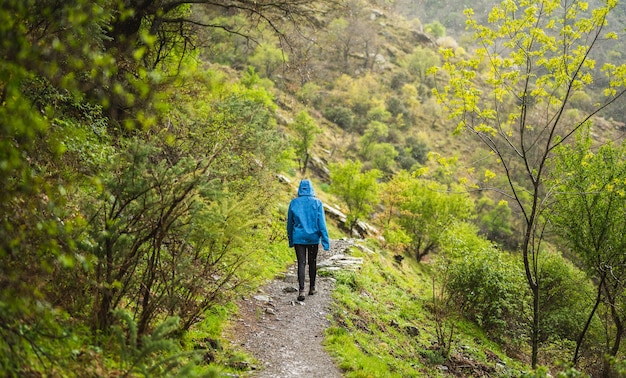 Chica en una acera rodeada de vegetación verde mientras llueve