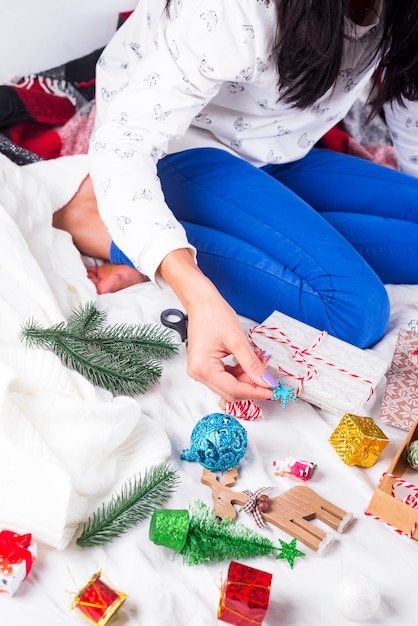 Chica en un acogedor suéter de punto decorado con una caja de regalo de Navidad