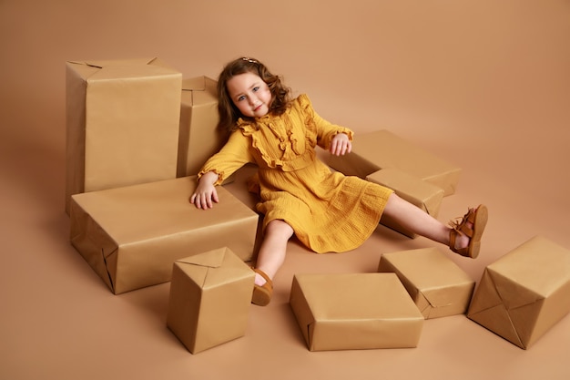 Chica acostada en medio de cajas dispersas con regalos como muñeca