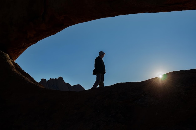 Chica activa viaja en la reserva natural de Spitzkoppe, mujer viajera caminando cerca de arcos de piedra