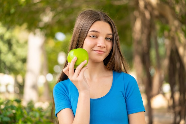 Chica adolescente al aire libre sosteniendo una manzana