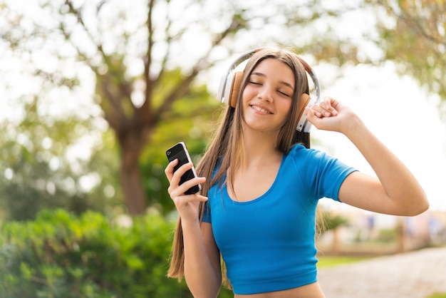 Chica adolescente al aire libre mediante teléfono móvil