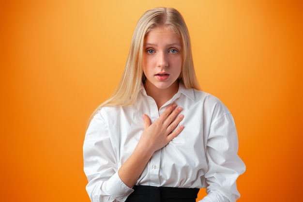 Chica adolescente alegre sorprendida contra el fondo naranja