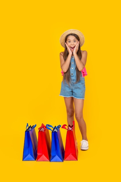 Chica adolescente asombrada con bolsas de compras en el espacio de copia de fondo amarillo