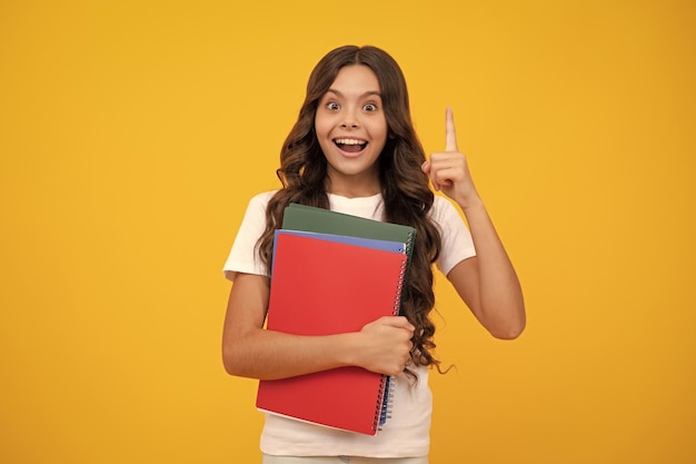 Chica adolescente asombrada Colegiala con libro de copia posando sobre fondo aislado Lección de literatura escuela de gramática Lector infantil intelectual Expresión emocionada alegre y alegre