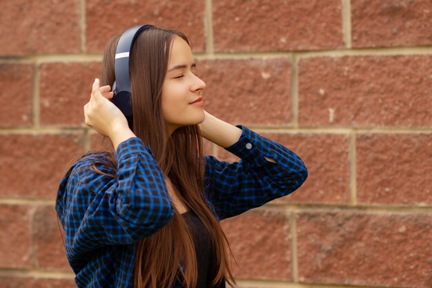 Chica adolescente con auriculares escuchando música en el teléfono, caminando, bailando en el verano, estilo de vida