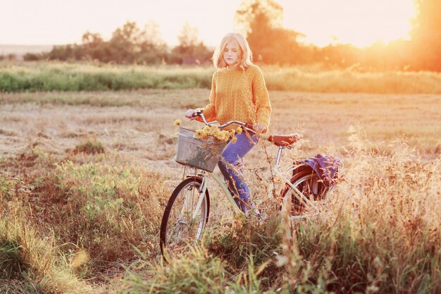 Chica adolescente en bicicleta en el campo de verano al atardecer