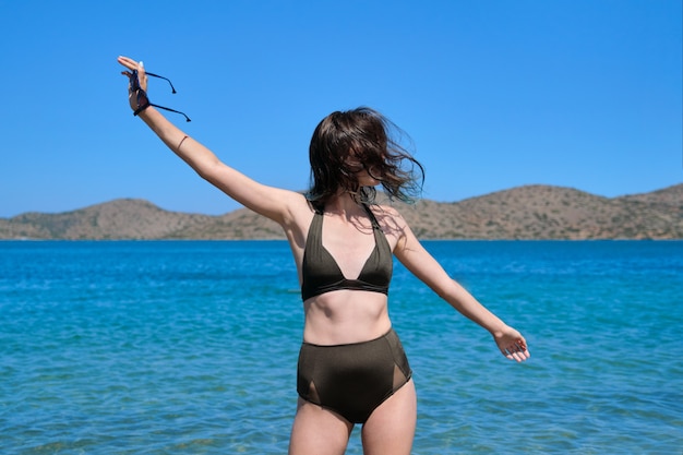 Chica adolescente en bikini de gafas de sol, disfrutando del agua de mar en la bahía. Diversión, belleza, naturaleza, relajación, juventud, vacaciones de verano en el mar
