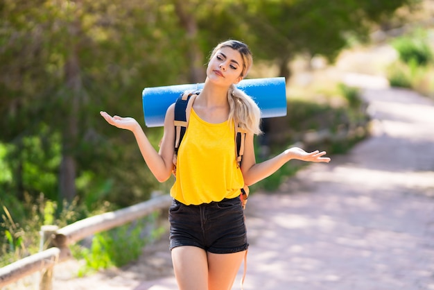 Chica adolescente caminando al aire libre haciendo dudas gesto