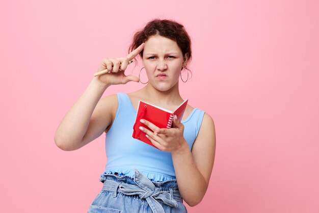 Chica adolescente en una camiseta azul con un bloc de notas rojo y un bolígrafo de emociones fondo aislado inalterado