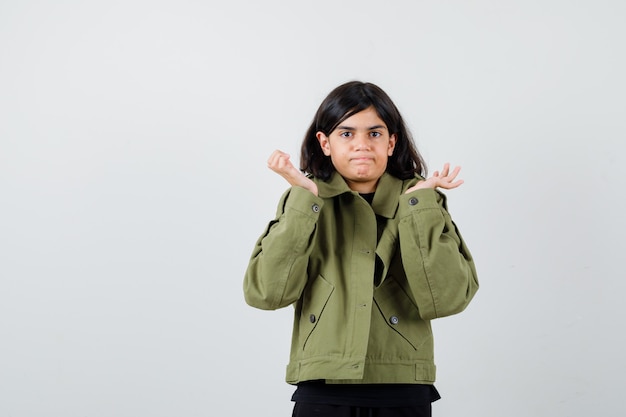 Chica adolescente en camiseta, chaqueta mostrando gesto de duda y mirando indeciso, vista frontal.