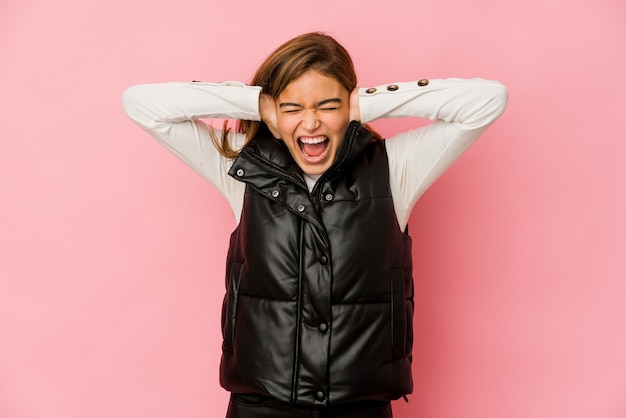 Foto chica adolescente caucásica flaca joven que cubre los oídos con las manos tratando de no escuchar un sonido demasiado fuerte.