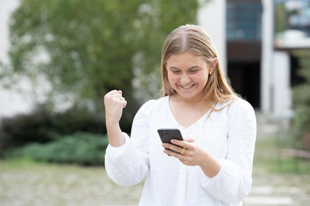 Chica adolescente celebrando buenos resultados por teléfono