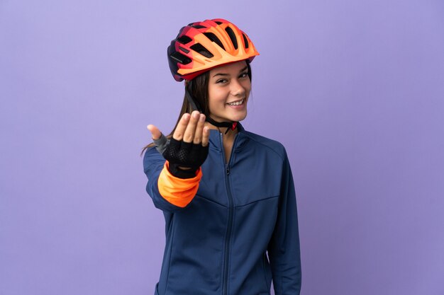 Chica adolescente ciclista que invita a venir con la mano. Feliz de que hayas venido