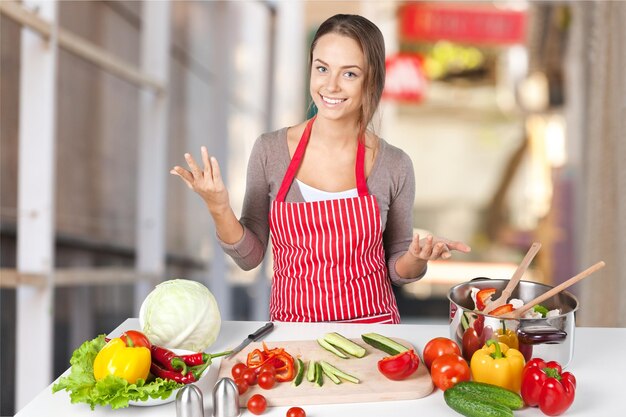 Chica adolescente cocinando ensalada de verduras en el fondo de la cocina