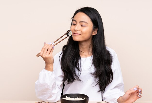 Chica adolescente comiendo comida asiática aislada en beige