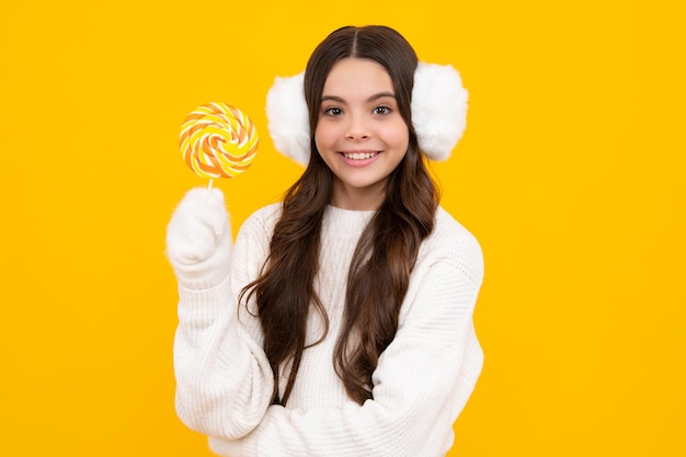 Chica adolescente comiendo piruleta de azúcar Dulces y dulces para niños Niño comer paleta de paleta sobre fondo amarillo aislado Tienda de dulces de caramelo delicioso Niña sonriente feliz