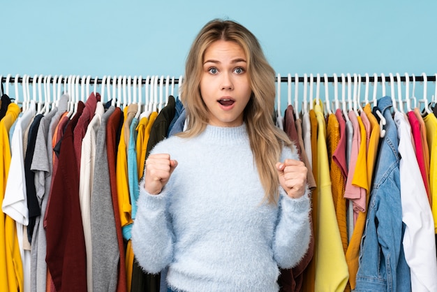 Chica adolescente comprando algo de ropa en azul celebrando una victoria en posición ganadora