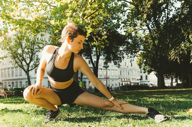 Chica adolescente de constitución muscular atlética haciendo estiramientos, haciendo yoga en el parque. Estilo de vida activo, al aire libre