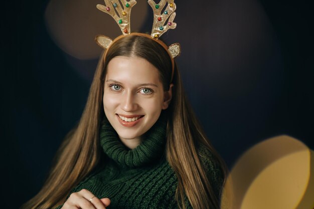 Foto chica adolescente con cuernos de ciervo de navidad en suéter verde se regocija