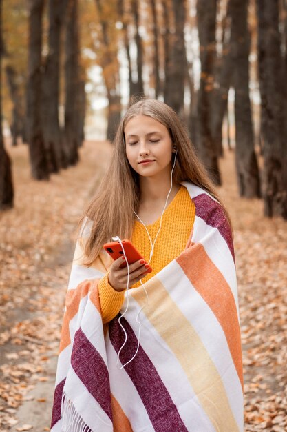 Chica adolescente dando un paseo por el parque y disfrutando de sus canciones favoritas, admirando la belleza de la naturaleza