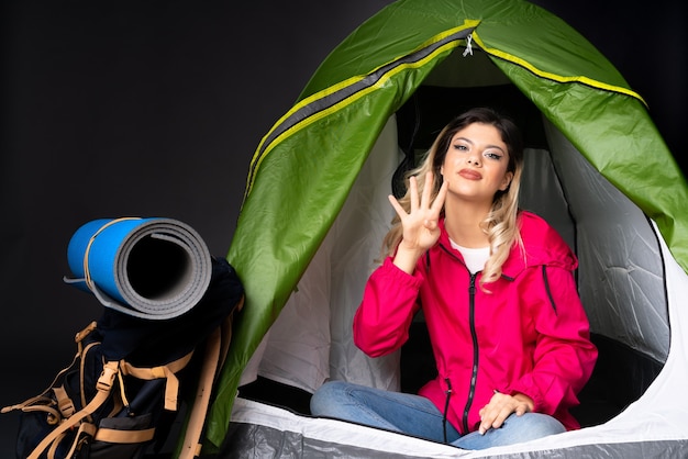 Foto chica adolescente dentro de una tienda de campaña verde