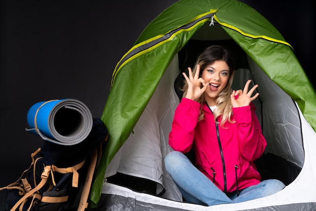 Foto chica adolescente dentro de una tienda de campaña verde