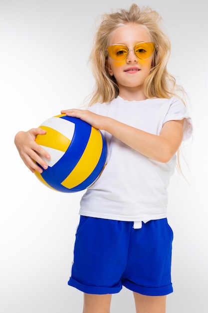 Chica adolescente deportiva en traje deportivo hacer ejercicios con baloncesto en la pared