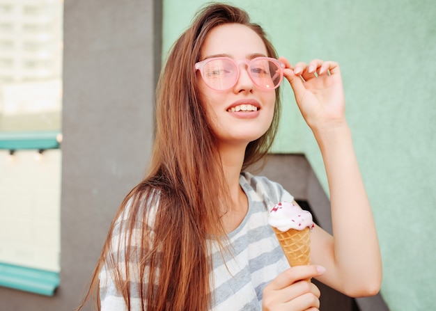 Chica adolescente divertida en gafas de sol cool hipster comiendo helado. Comida de verano