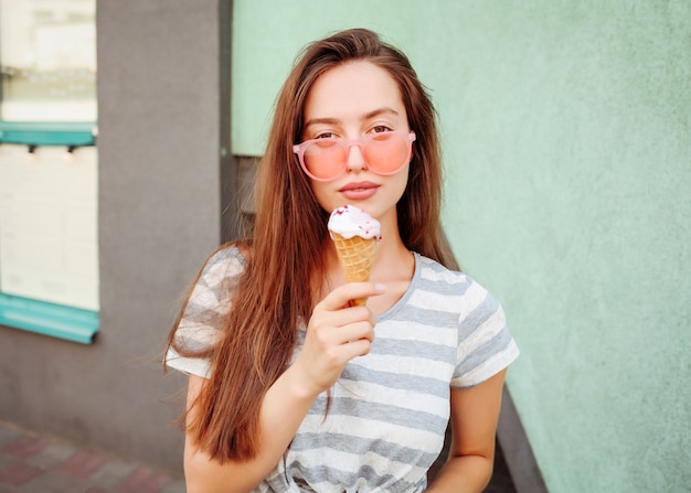 Chica adolescente divertida en gafas de sol cool hipster comiendo helado. Comida de verano