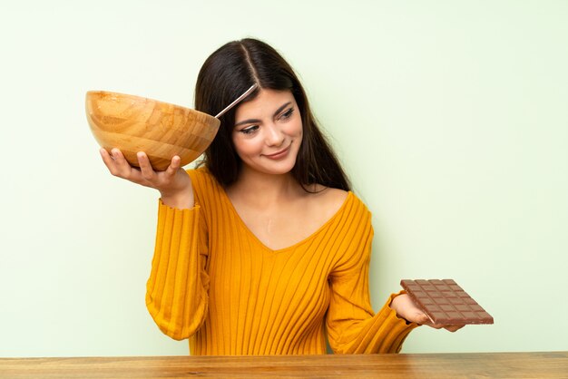 Chica adolescente con ensalada y chocolat con dudas.