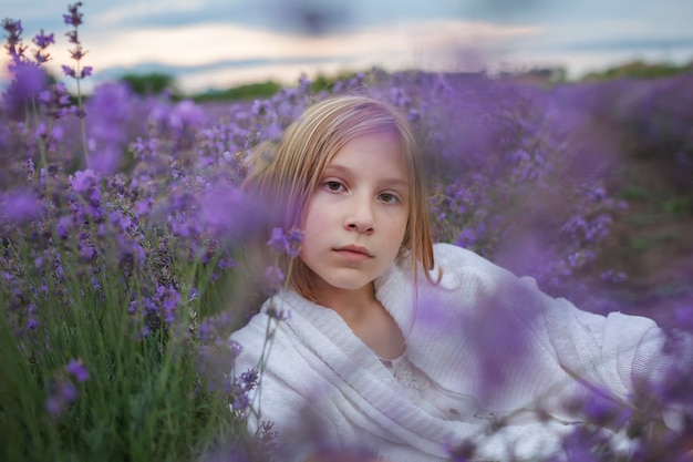 Chica adolescente de ensueño se sienta en la belleza del campo de lavanda de la naturaleza paisaje tranquilo de estilo de vida de verano