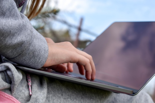 Chica adolescente estudiando en una computadora portátil Educación a distancia Colegiala feliz en el parque con la computadora