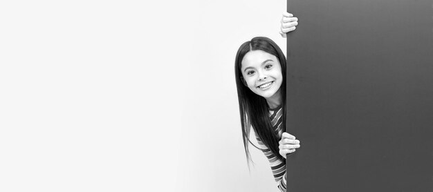 Chica adolescente feliz detrás de una hoja de papel rosa con lugar vacío para publicidad de espacio de copia Cartel horizontal de cara de niño Chica adolescente banner de retrato aislado con espacio de copia