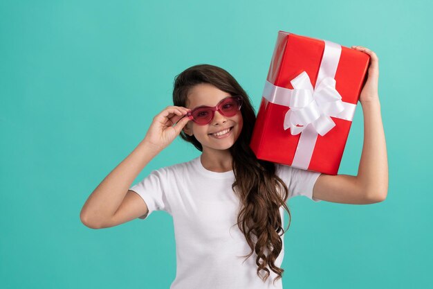 Chica adolescente feliz de moda en gafas de sol con caja de regalo, cumpleaños.