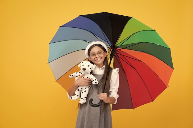 Chica adolescente feliz bajo un paraguas colorido en la temporada de otoño mantenga la infancia feliz del juguete