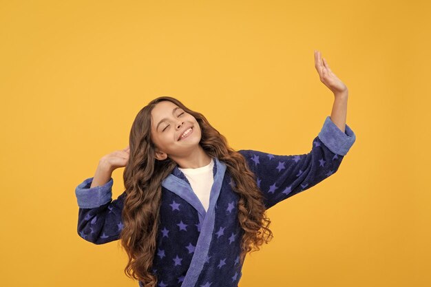 Chica adolescente feliz con el pelo rizado que se extiende en pijama cómodo buenos días