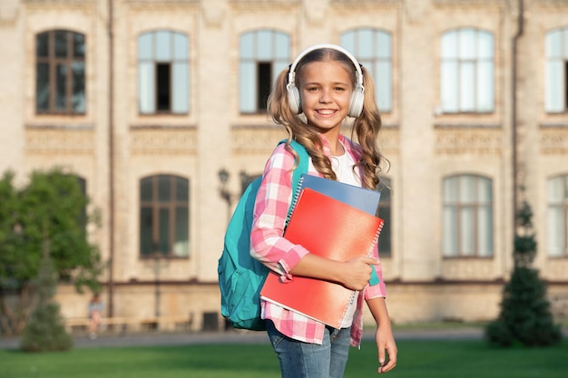 Chica adolescente feliz regreso a la escuela música al aire libre