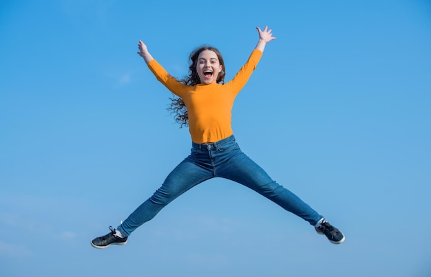 Chica adolescente feliz salta alto en la felicidad de fondo del cielo
