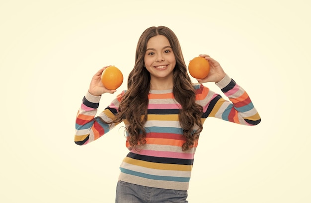 Chica adolescente feliz en suéter colorido con fruta naranja aislada en vitaminas blancas