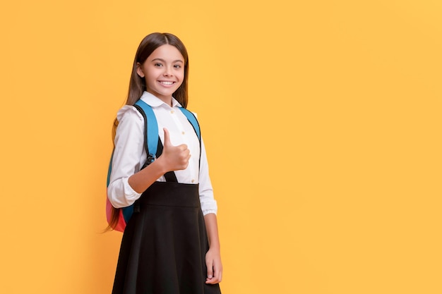 Chica adolescente feliz en uniforme escolar llevar mochila mostrando pulgar arriba copia espacio 1 de septiembre